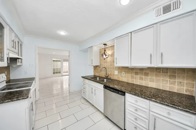 a kitchen with granite countertop white cabinets and stainless steel appliances