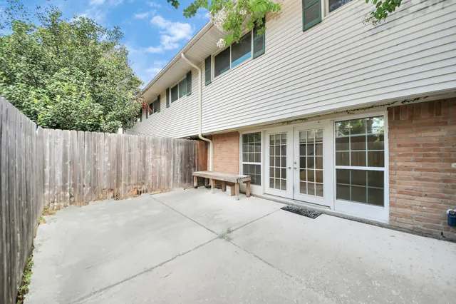 a backyard of a house with table and chairs and wooden fence