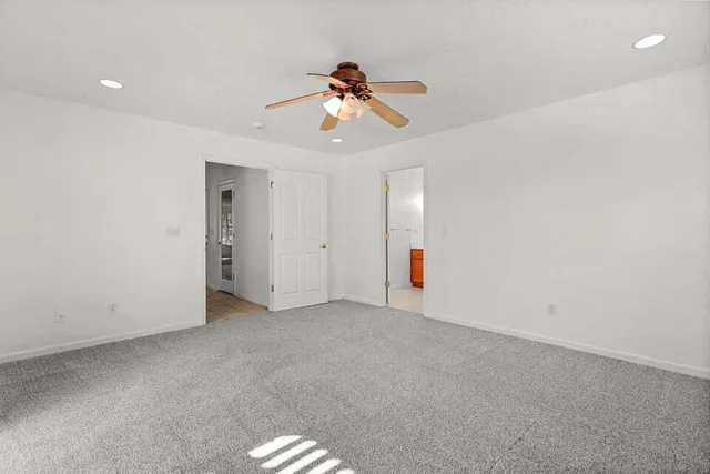 an empty room with a ceiling fan and window