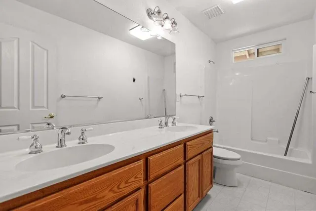a bathroom with a granite countertop sink a toilet and shower