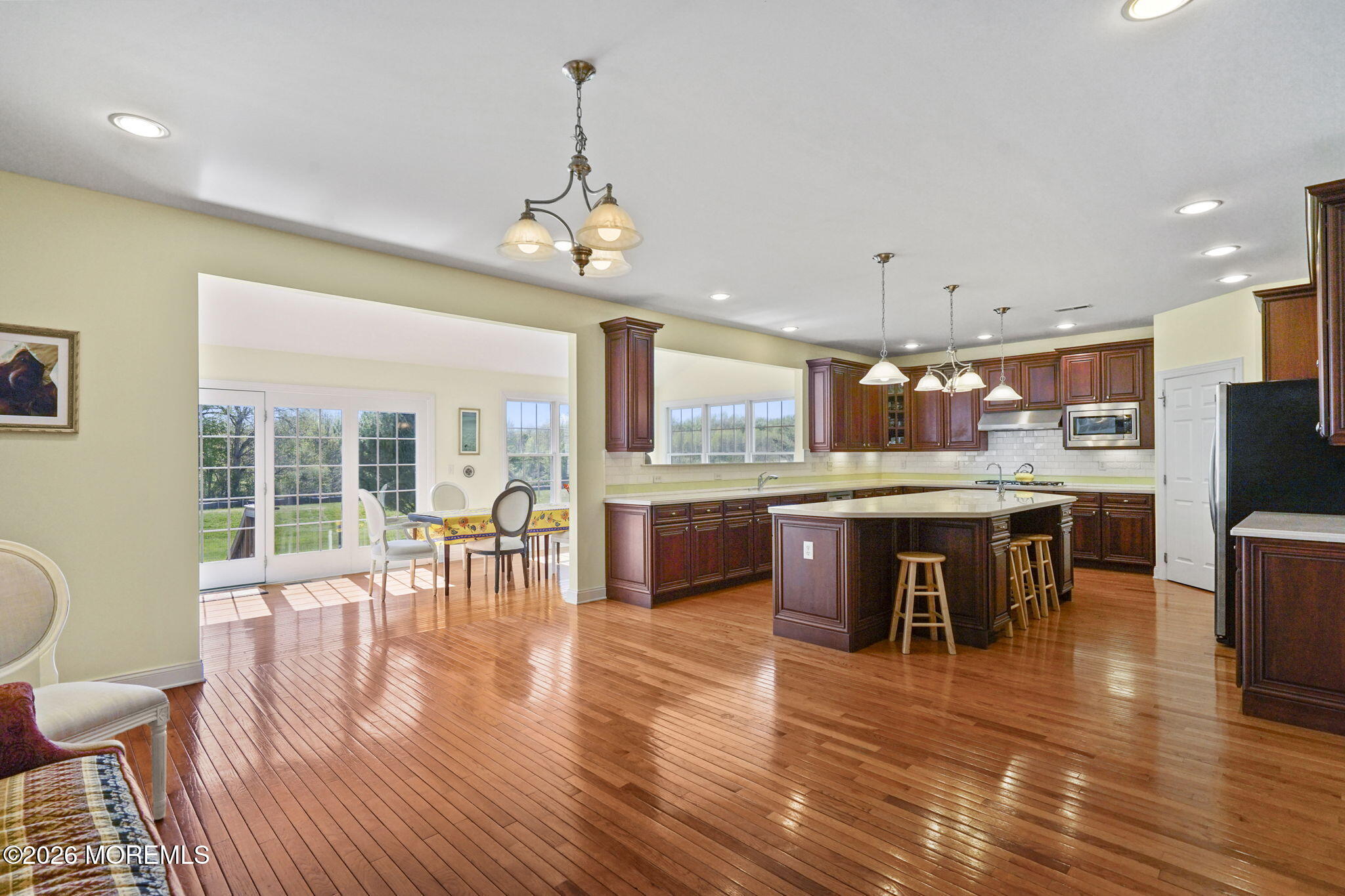 10 Rockingham Court Manalapan, NJ 07726 - Photo 25 of 91 a open kitchen with stainless steel appliances granite countertop a stove top oven a sink a dining table and chairs with wooden floor