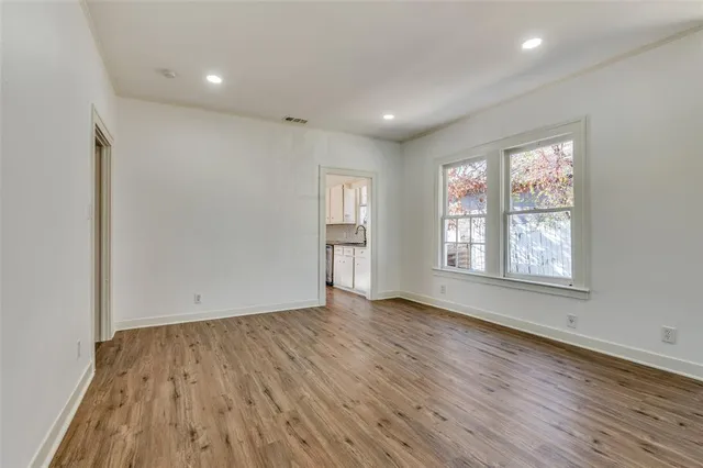 a view of an empty room with wooden floor and a window