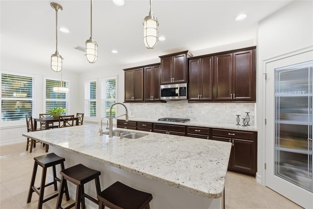 12106 Perennial Place Lakewood Ranch, FL 34211 - Photo 14 of 66 a kitchen with stainless steel appliances granite countertop a sink a stove and chairs