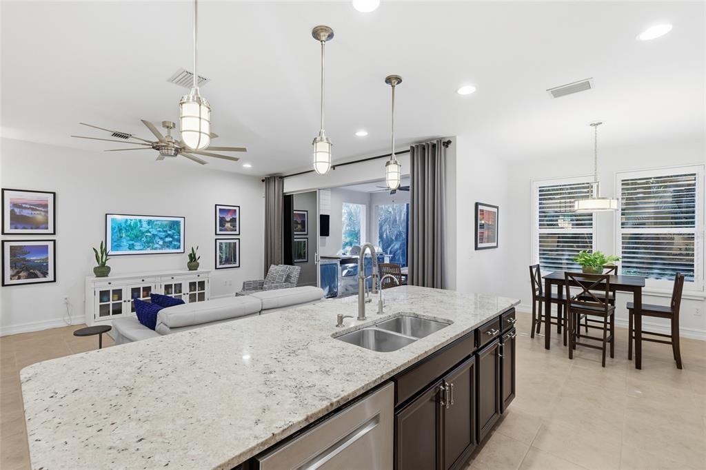 12106 Perennial Place Lakewood Ranch, FL 34211 - Photo 16 of 66 a kitchen with granite countertop a sink a counter top space appliances and living room view