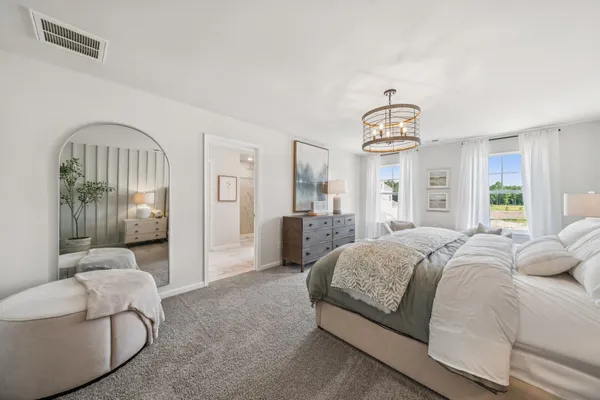 a spacious bedroom with a bed and a chandelier