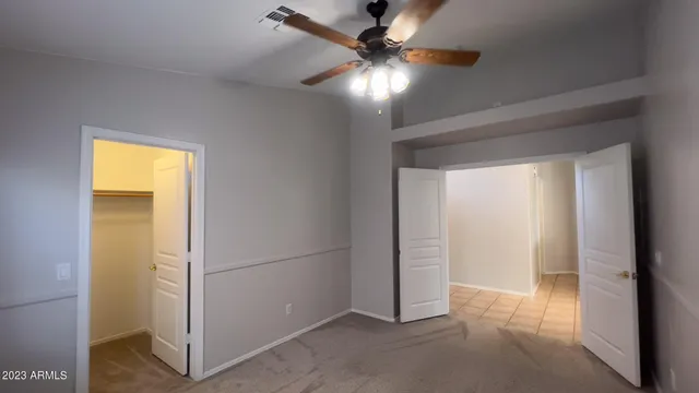 an empty room with closet and a chandelier fan