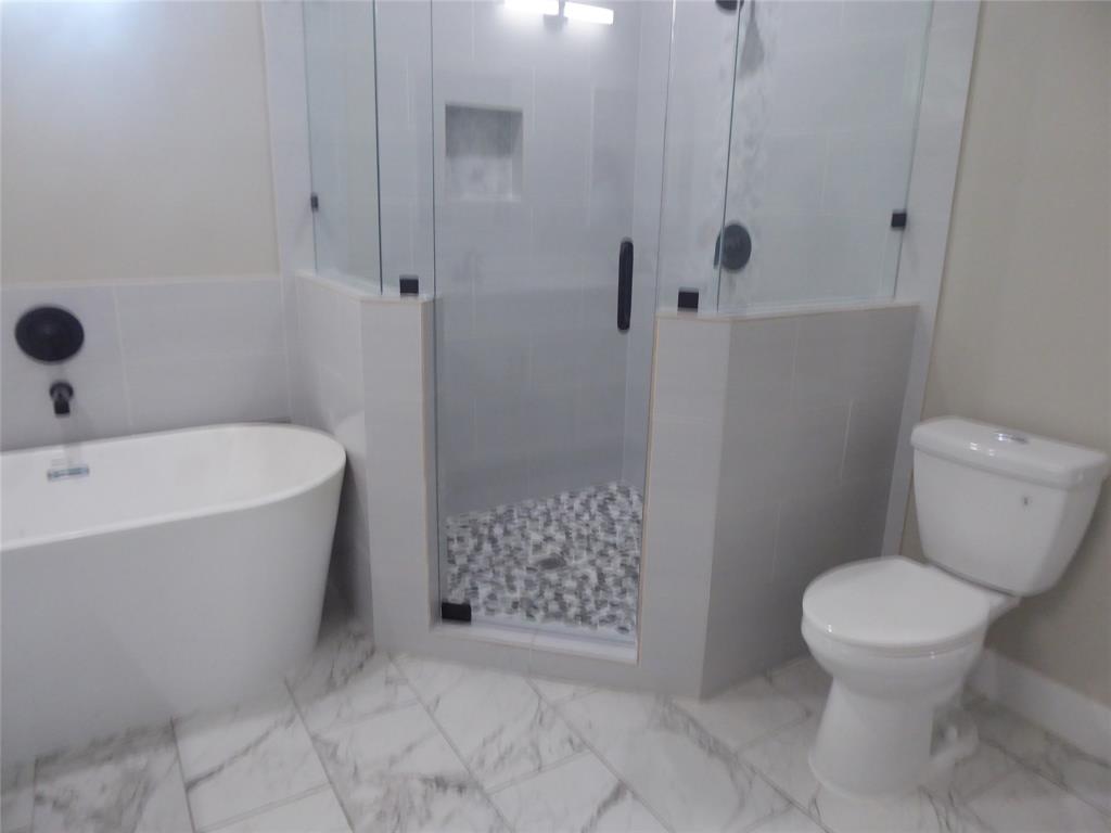 230 Third Street Wilmer, TX 75172 - Photo 14 of 40 a bathroom with a toilet and shower