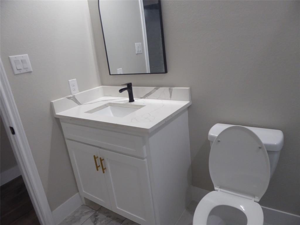 230 Third Street Wilmer, TX 75172 - Photo 38 of 40 a bathroom with a toilet sink and mirror