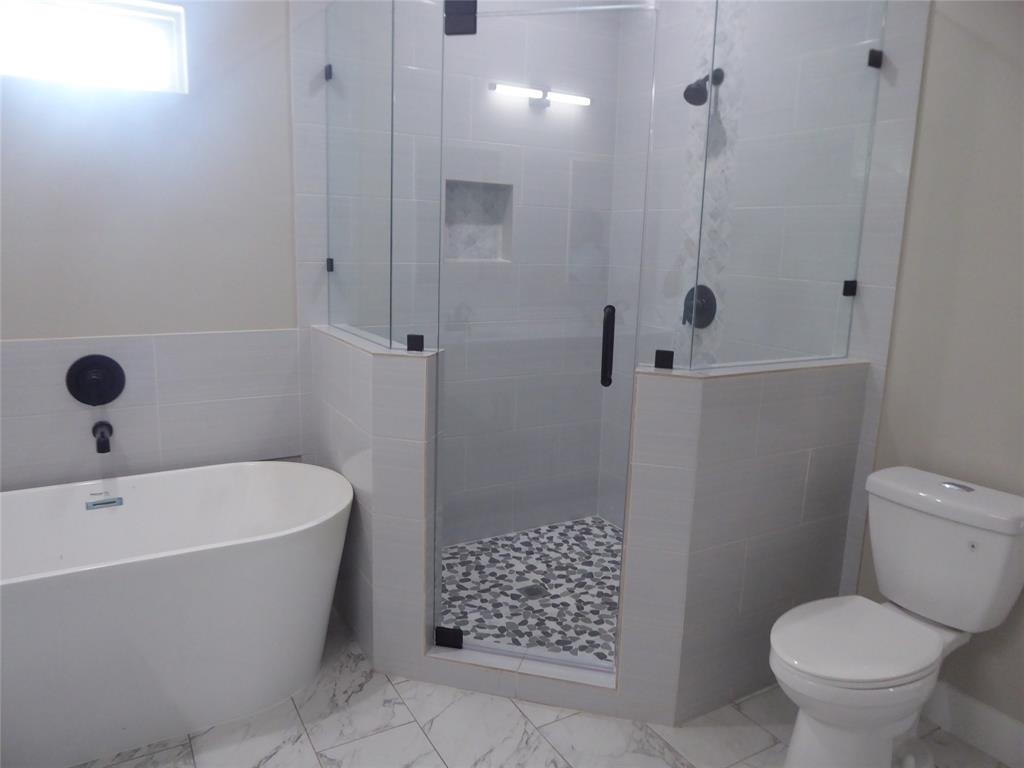 230 Third Street Wilmer, TX 75172 - Photo 9 of 40 a white bath tub sitting next to a toilet