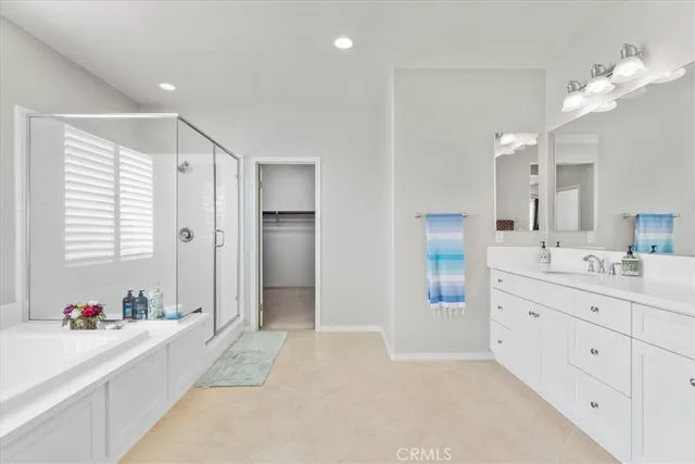 a spacious bathroom with a double vanity sink a mirror a bathtub and a shower