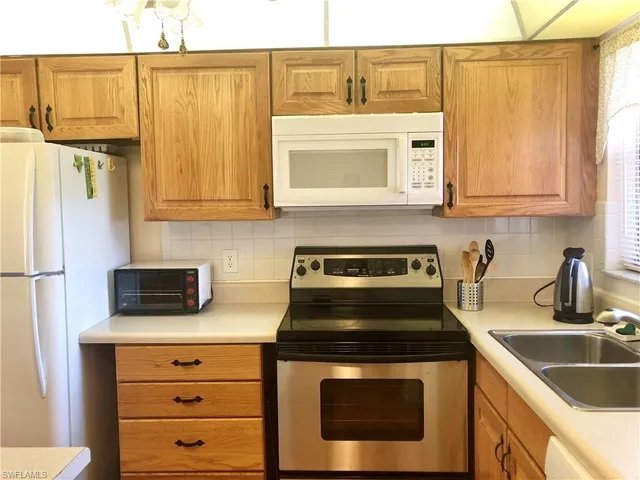 a kitchen with stainless steel appliances granite countertop a refrigerator stove and sink with wooden cabinets