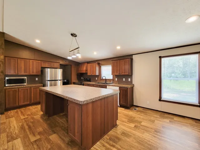 a kitchen with kitchen island a sink a counter top space stainless steel appliances and cabinets