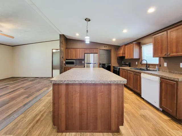 a kitchen with kitchen island a sink stainless steel appliances and cabinets
