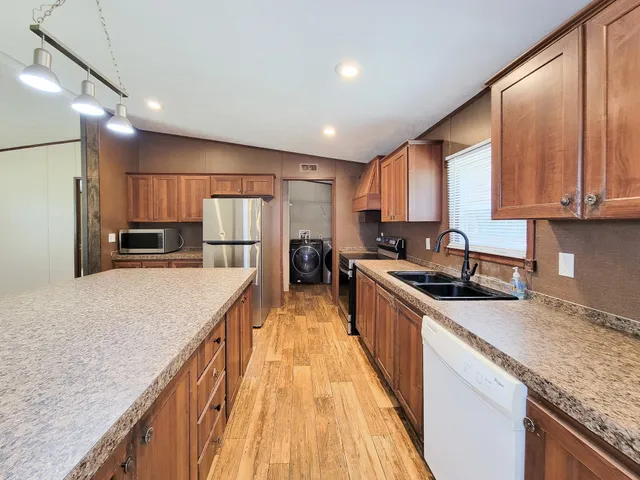 a kitchen with kitchen island granite countertop wooden cabinets a refrigerator and a sink