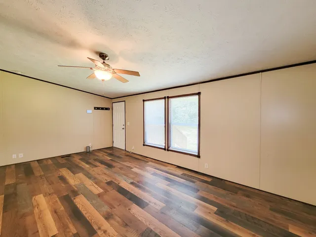 a view of an empty room with windows and chandelier fan