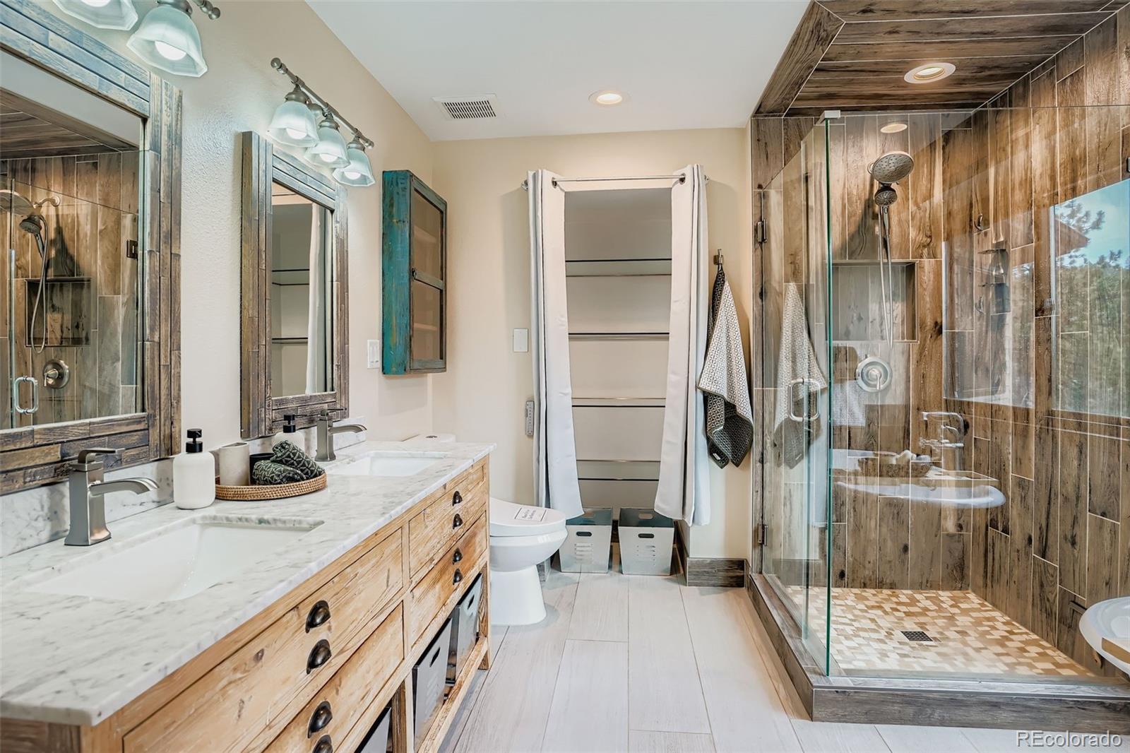 13342 Douglass Ranch Drive Pine, CO 80470 - Photo 16 of 31 a bathroom with a granite countertop sink a mirror and shower