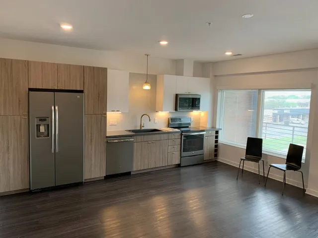 a large white kitchen with wooden floor and stainless steel appliances