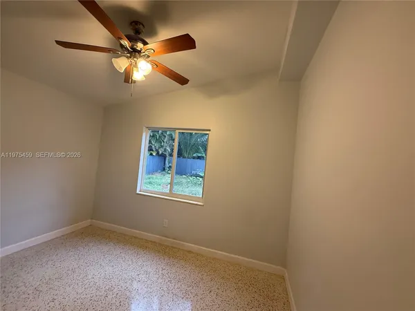 an empty room with a window and a fan