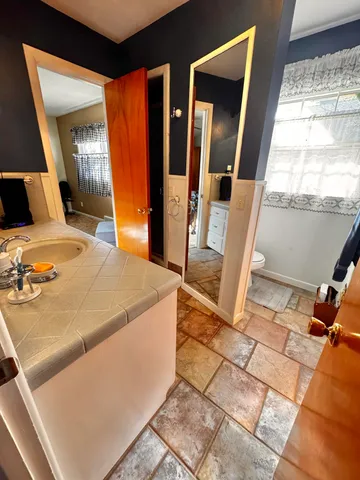 a bedroom with a bed and dresser with wooden floor