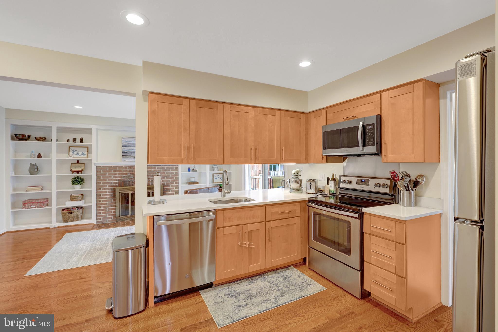 a kitchen with stainless steel appliances granite countertop a stove top oven a sink dishwasher a dining table and chairs with wooden floor