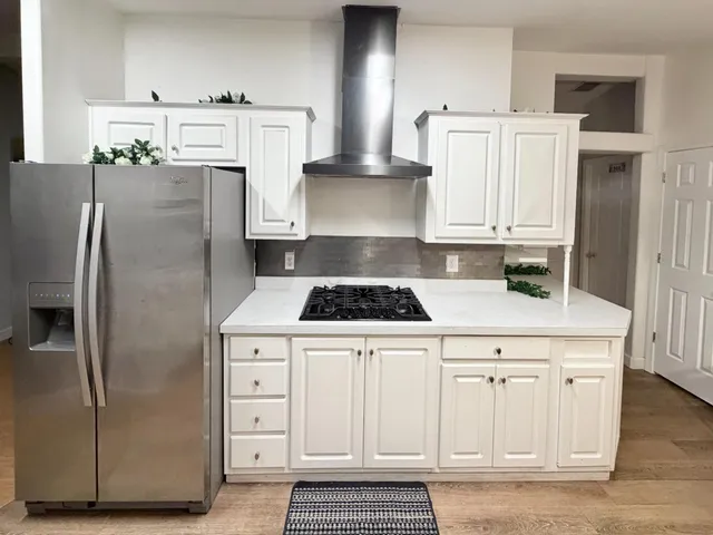 a kitchen with white cabinets and refrigerator