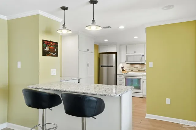 a view of kitchen with granite countertop refrigerator and cabinets