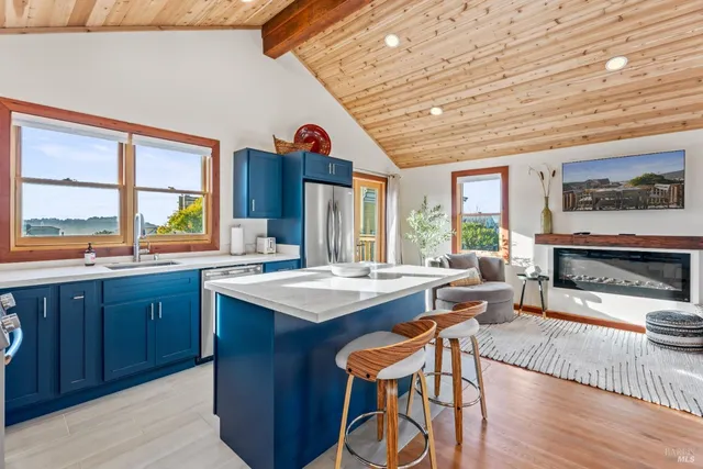 a kitchen with stainless steel appliances a refrigerator a sink a stove and white cabinets with wooden floor