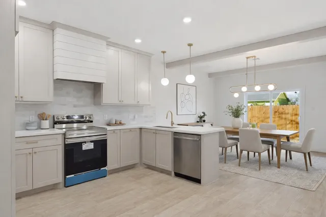 a kitchen with lots of white cabinets appliances and a sink