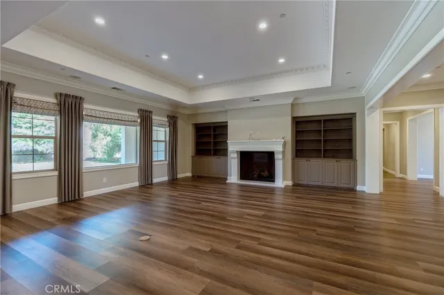 a view of an empty room with wooden floor fireplace and a window