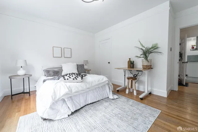 a bedroom with a bed table and wooden floor