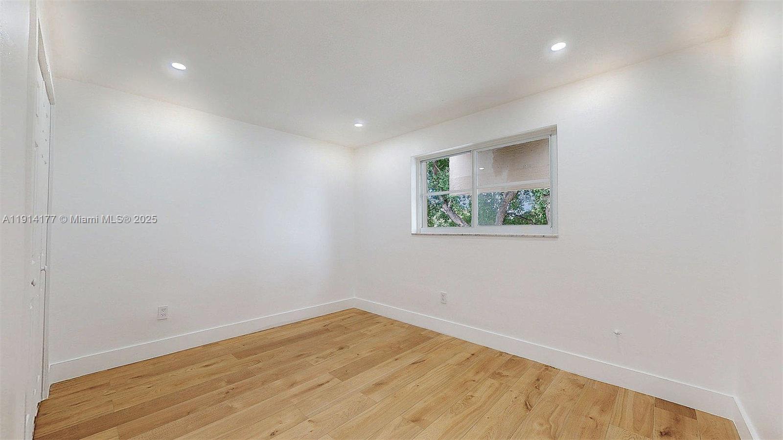 1201 Southwest 42nd Avenue, Unit 211 Miami, FL 33134 - Photo 11 of 19 an empty room with a wooden floor and window