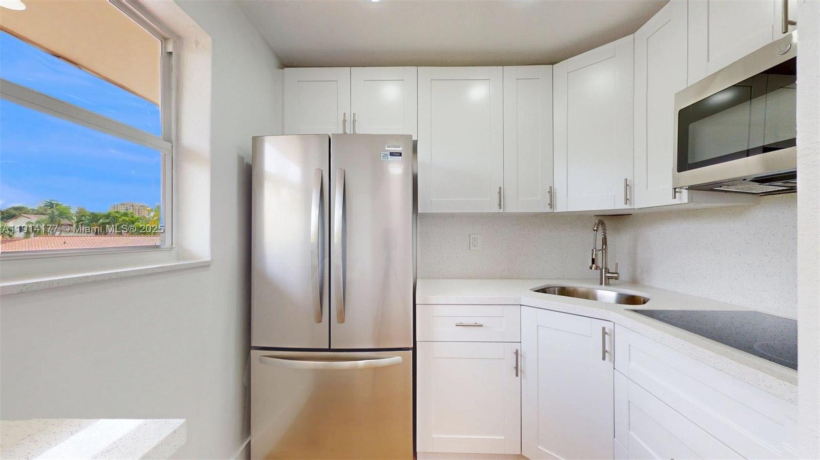 1201 Southwest 42nd Avenue, Unit 211 Miami, FL 33134 - Photo 5 of 19 a kitchen with stainless steel appliances white cabinets and a refrigerator