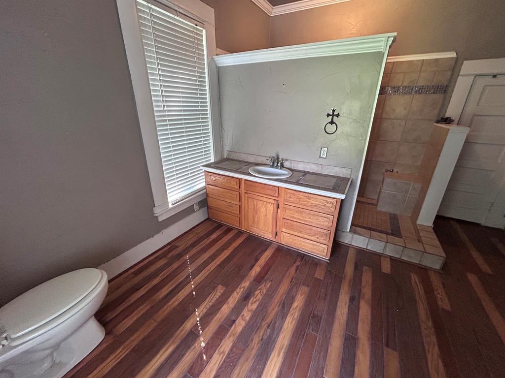 116 Gas Plant Road Doyline, LA 71023 - Photo 16 of 19 Wood-finish flooring with a vanity featuring a built-in sink and storage cabinetry, alongside a tiled shower enclosure