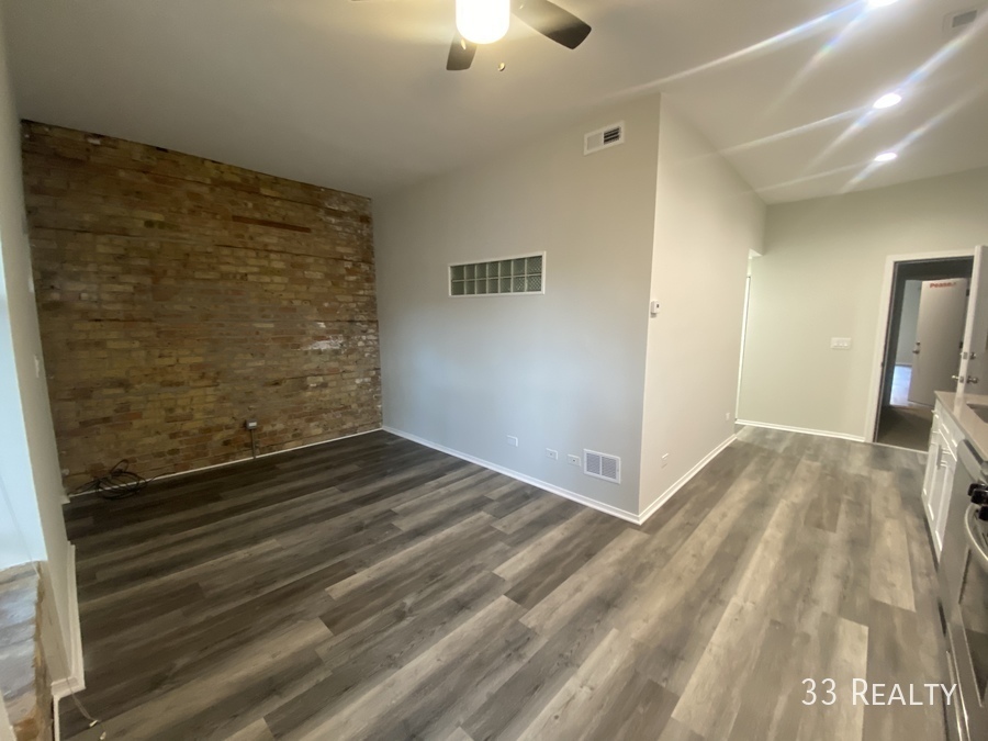 1246 North Cleaver Street, Unit 1R Chicago, IL 60642 - Photo 4 of 8 a view of a livingroom with wooden floor and chandelier