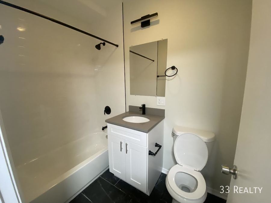 1246 North Cleaver Street, Unit 1R Chicago, IL 60642 - Photo 6 of 8 a bathroom with a granite countertop sink toilet and shower