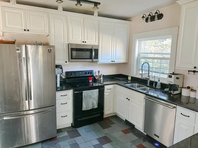 a kitchen with granite countertop a refrigerator sink and microwave