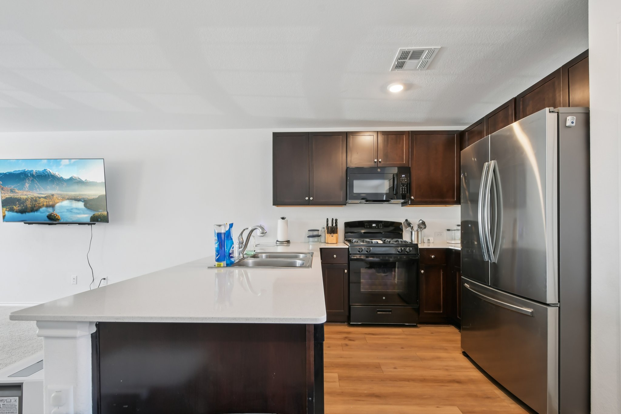 14116 Mussel Run Elgin, TX 78621 - Photo 25 of 25 Kitchen with black appliances, dark wood finish cabinetry, a peninsula, light wood-type flooring, and recessed lighting