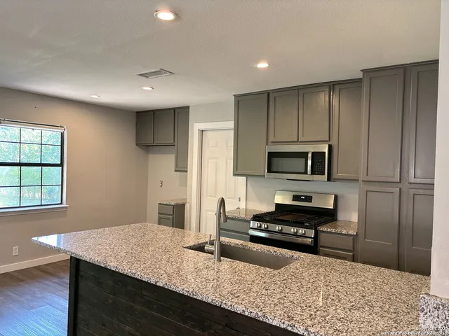 a kitchen with stainless steel appliances granite countertop a sink stove and refrigerator