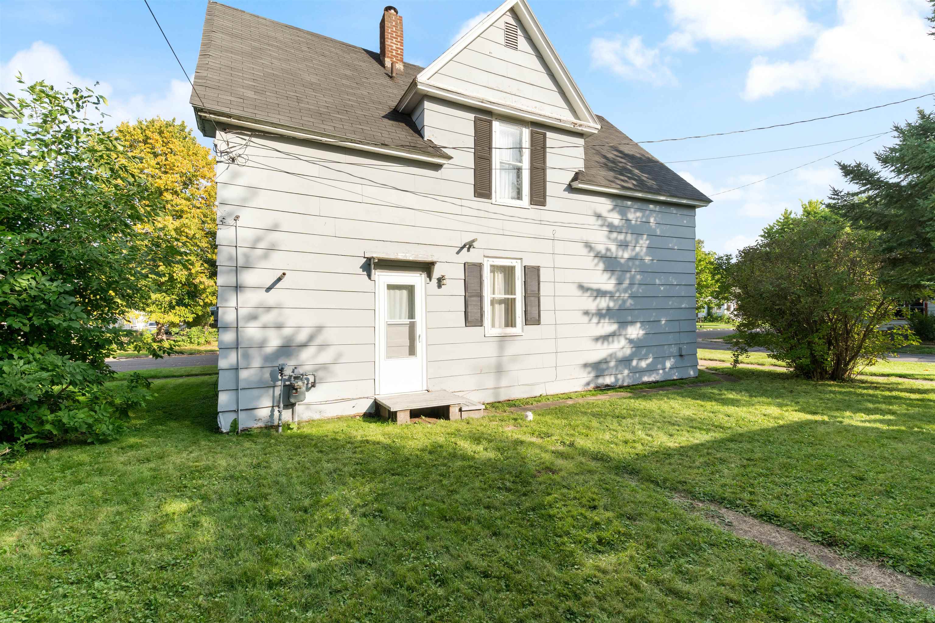1301 North 11th Street Superior, WI 54880 - Photo 14 of 21 Rear view of house featuring a chimney, a yard, and a shingled roof