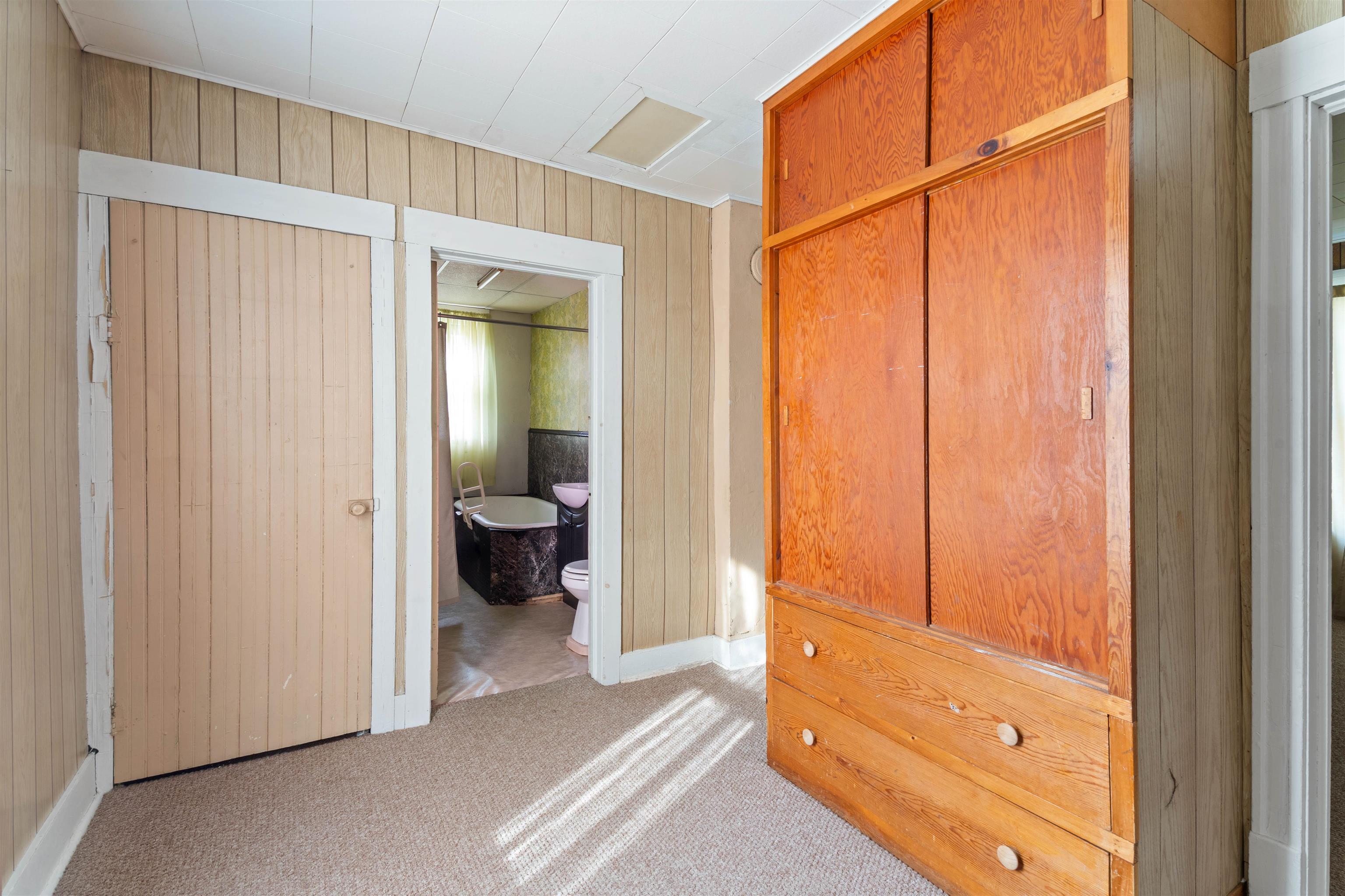 1301 North 11th Street Superior, WI 54880 - Photo 8 of 21 Bedroom with wood walls, attic access, light colored carpet, and connected bathroom
