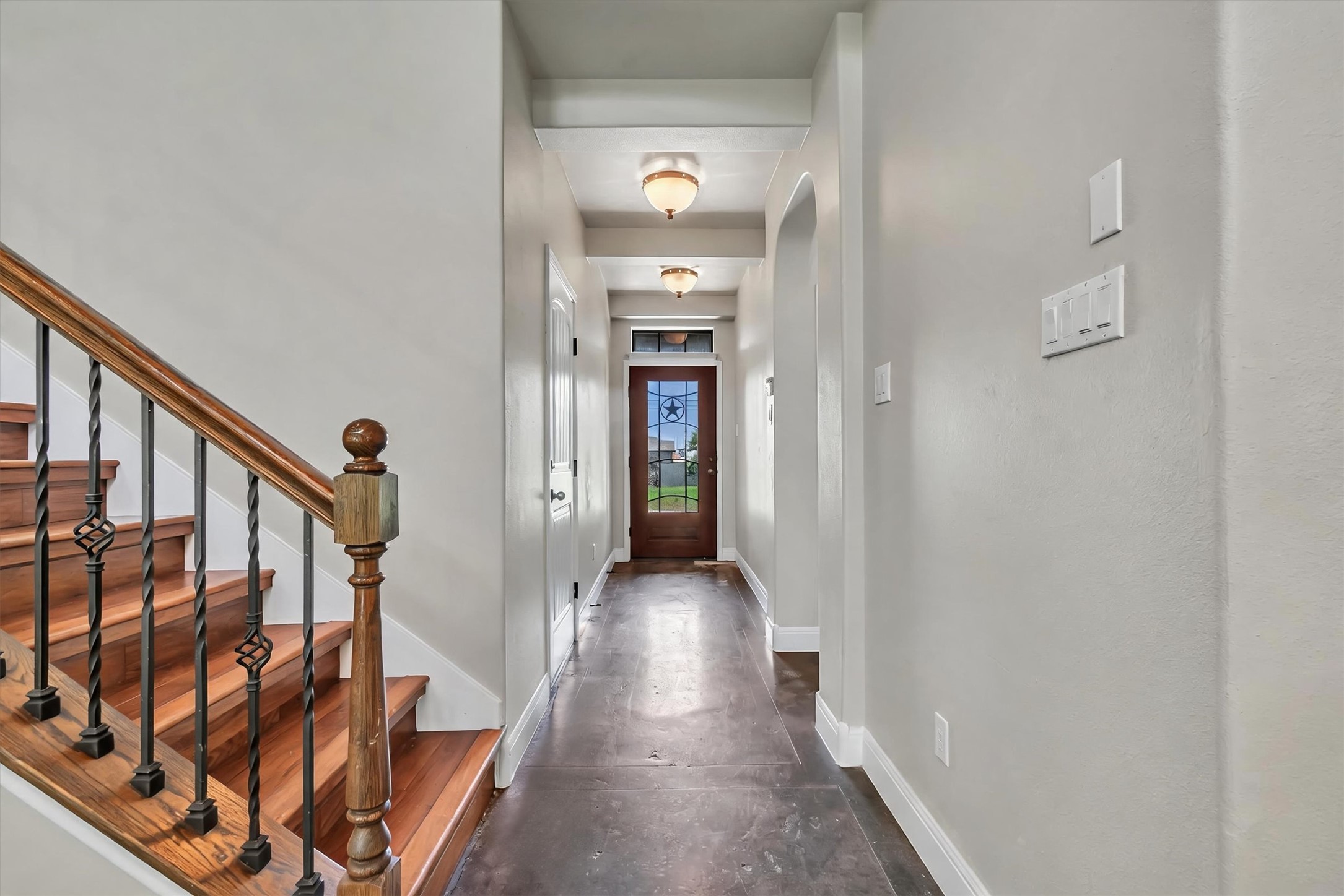 1010 Immanuel Road, Unit 103 Pflugerville, TX 78660 - Photo 5 of 30 A welcoming entryway with a staircase featuring a wooden handrail and ornate iron balusters.