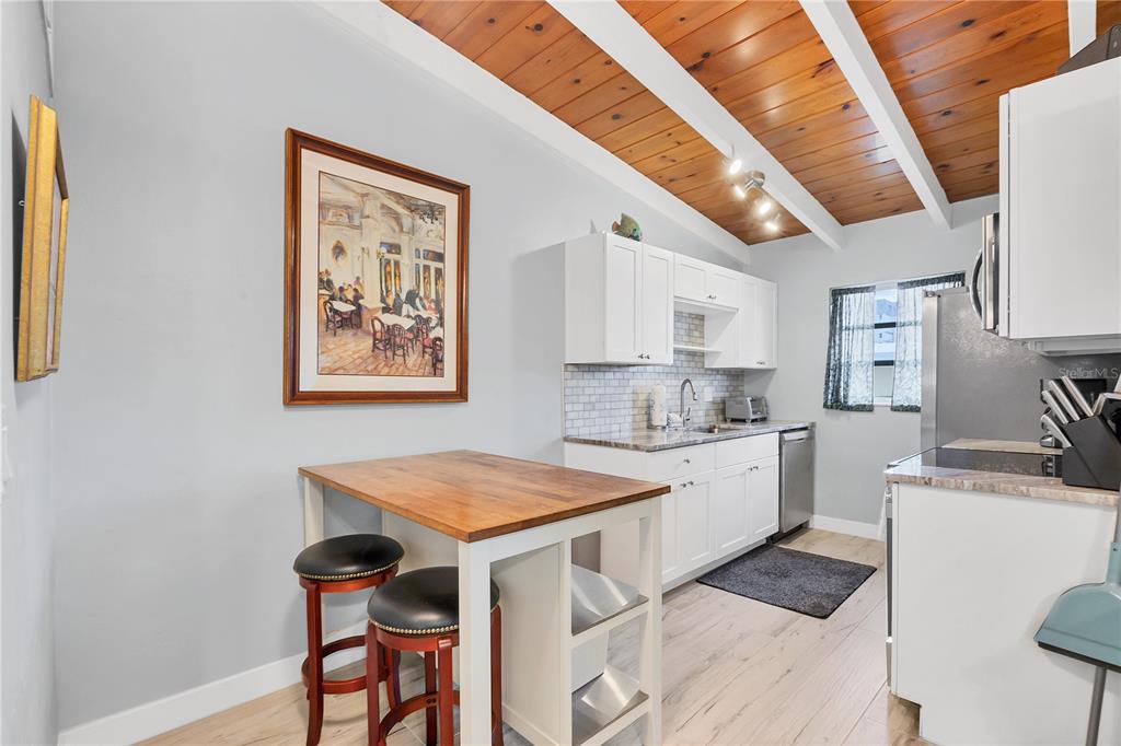 6006 Midnight Pass Road, Unit 21 Sarasota, FL 34242 - Photo 7 of 24 a kitchen with stainless steel appliances granite countertop a stove top oven a sink a refrigerator and white cabinets with wooden floor