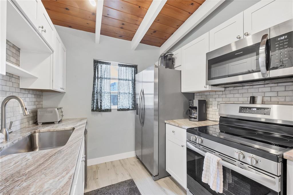 6006 Midnight Pass Road, Unit 21 Sarasota, FL 34242 - Photo 8 of 24 a kitchen with stainless steel appliances granite countertop a sink stove and refrigerator