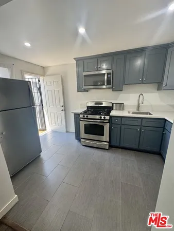 a kitchen with stainless steel appliances a sink a stove a microwave a refrigerator a window