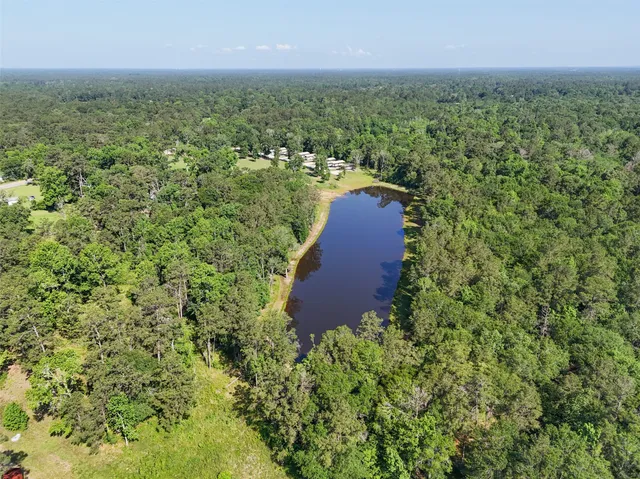 an aerial view of residential house with outdoor space and trees all around