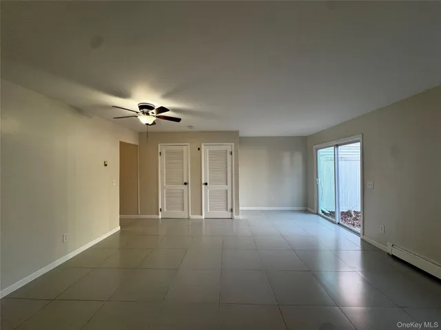 an empty room with chandelier fan and windows