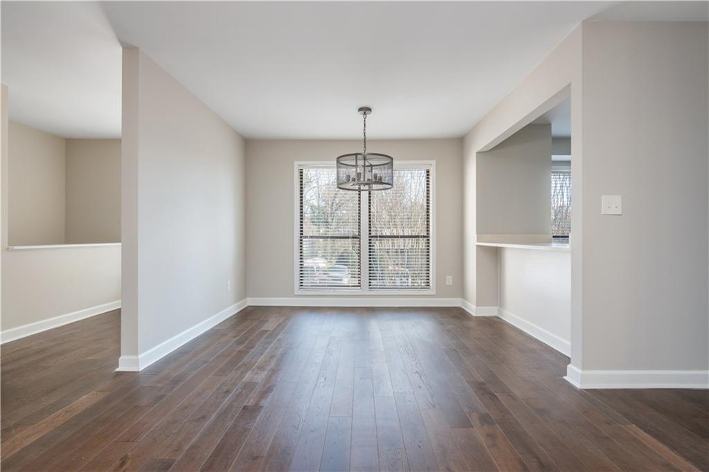1211 Wynnes Ridge Circle Marietta, GA 30067 - Photo 4 of 35 an empty room with wooden floor chandelier and windows
