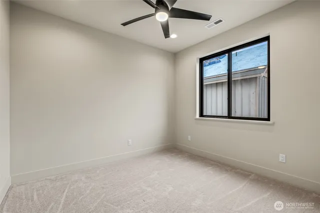 an empty room with a window and ceiling fan