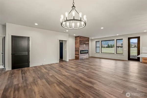 an empty room with wooden floor chandelier and windows