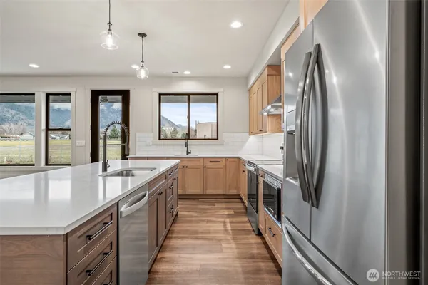 a large kitchen with stainless steel appliances granite countertop a sink and dishwasher a refrigerator with wooden floor